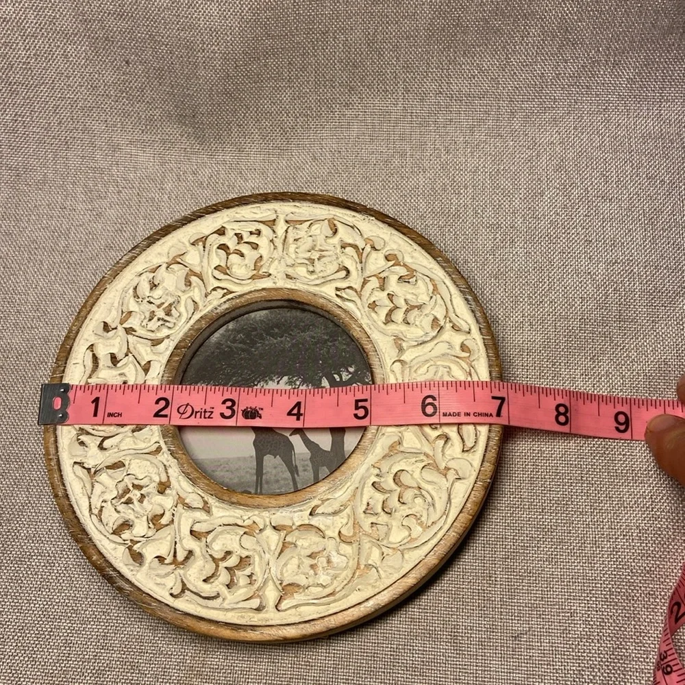 Decorative round, carved wooden picture frame with a distressed white finish.
